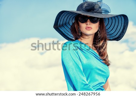 Portrait of a charming lady in beautiful elegant dress and hat against the sky.