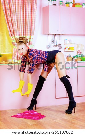 Pretty sexy pin-up girl cleans her glamorous pink kitchen. Retro style. Fashion.