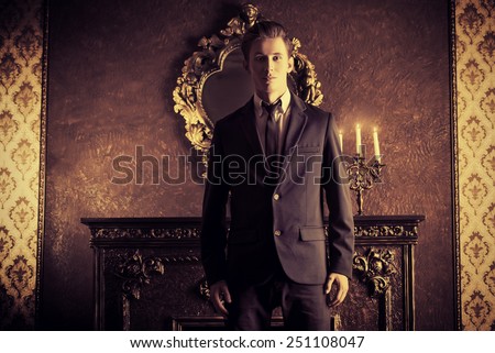 Handsome respectable man in elegant suit stands in a room with classic vintage style. Business. Fashion.