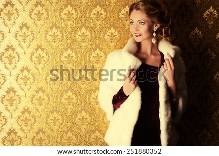 Elegant young woman in  evening dress and mink fur jacket posing in vintage interior. Jewellery.  Fashion shot.