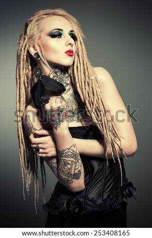 Gorgeous sexy girl with black make-up and long dreadlocks. Gothic style. Fashion. Cosmetics, hairstyle. Tattoo.