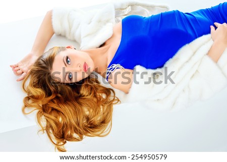 Stunning young woman posing in fashionable dress and mink fur jacket. Luxury, rich lifestyle. Fashion shot. Isolated over white background.