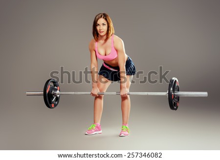 Strong young woman with beautiful athletic body doing exercises with barbell. Fitness, bodybuilding. Health care.