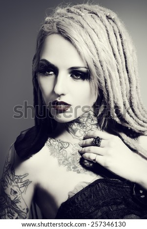 Gorgeous sexy girl with black make-up and long dreadlocks. Gothic style. Fashion. Cosmetics, hairstyle. Tattoo.