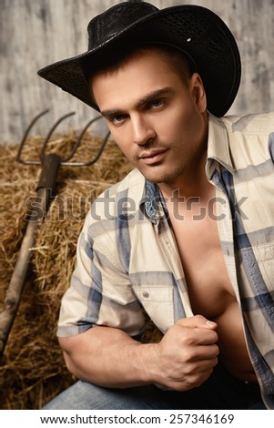 Sexy cowboy on a haystack. Western style.