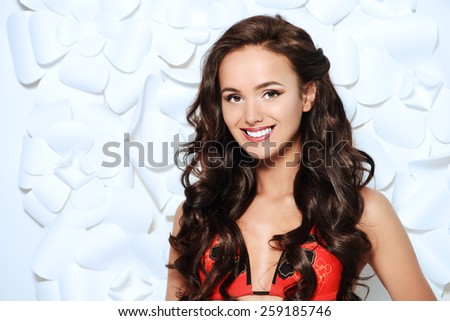 Fashion shot of a beautiful brunette woman in bikini posing over background of white paper flowers. Beauty, fashion. Spa, healthcare.