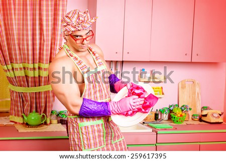 Handsome muscular man in an apron cooking in the pink kitchen. Love concept. Valentine\'s day.