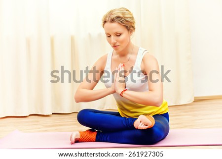Beautiful athletic girl doing yoga exercises indoor. Lotus pose. Meditation.