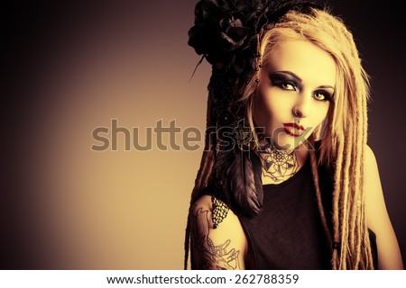 Gorgeous sexy girl with black make-up and long dreadlocks. Gothic style. Fashion. Cosmetics, hairstyle. Tattoo. Vintage, sepia.