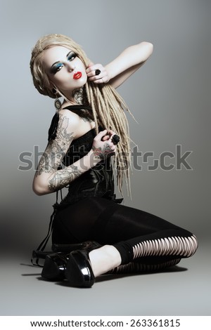 Full length portrait of a gorgeous sexy girl with black make-up and long dreadlocks. Gothic style. Fashion. Cosmetics, hairstyle. Tattoo.