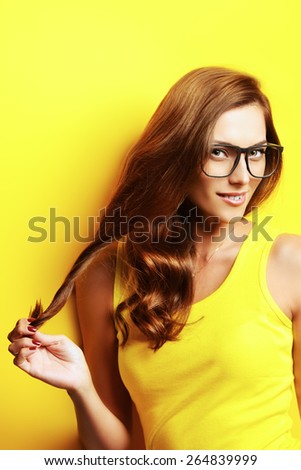 Beauty portrait of a happy young woman in spectacles and bright yellow dress over yellow background. Beauty, fashion. Optics.