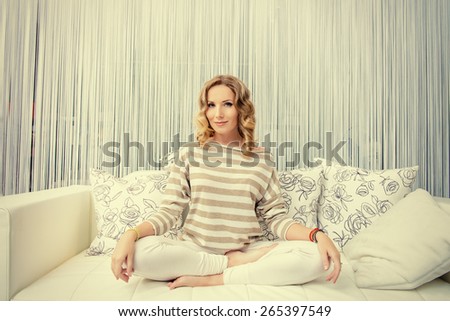 Happy young woman having a rest in her bedroom and doing yoga exercises. Home interior, furniture. Lifestyle.