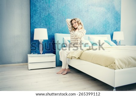 Happy elegant woman having a rest in her bedroom. Home interior, furniture. Lifestyle.