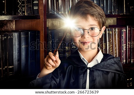 A boy stands with magic wand in the library by the bookshelves with many old books. Fairy tales. Vintage style.