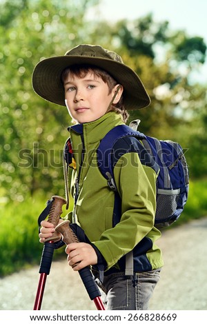 Portrait of a cute 7 years old boy in tourist clothes posing outdoor. Summer day.