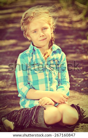 Funny little girl in the countryside. Happy childhood. Western style, jeans.