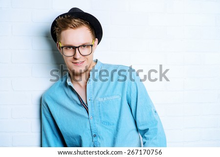 Portrait of a modern young man standing by the brick wall. Beauty, fashion. Hipster style.