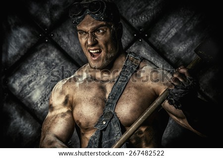 Strong aggressive coal miner with a hammer over dark grunge background. Mining industry. Art concept.