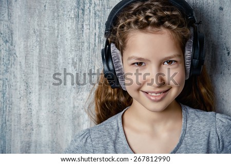 Cool teen girl enjoys the music in headphones. Studio shot.