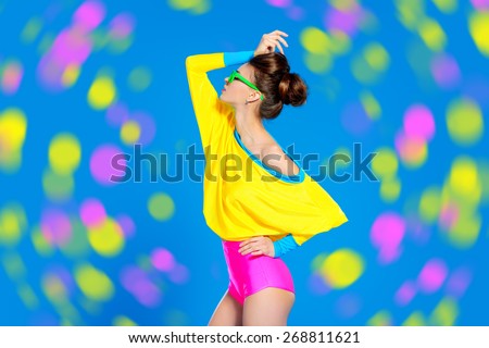 Glamorous fashion model posing in vivid colourful clothes and sunglasses. Bright fashion. Optics, eyewear. Studio shot.