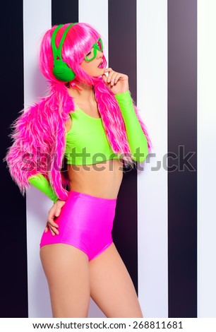 Trendy DJ girl in bright colorful clothes and headphones posing over black-and-white stripes. Party style. Fashion studio shot.