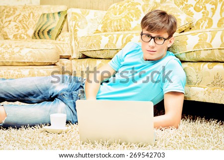 Casual young man sitting on the floor with a laptop in the comfort of his home.
