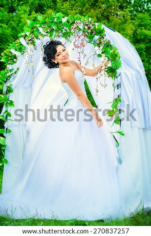 Beautiful elegant asian bride stands under the wedding arch. Wedding dress and accessories. Wedding decoration.