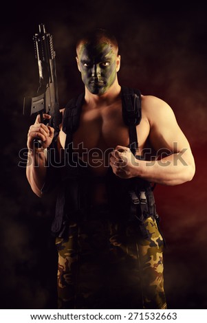 A soldier in war paint holding the automatic rifles. Military, war. Special forces.