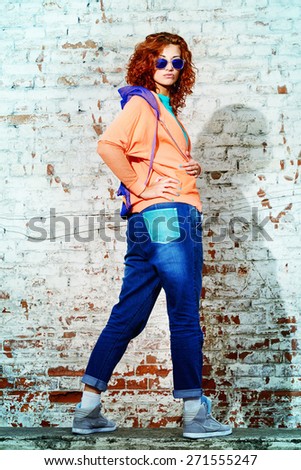 Young stylish girl in the city. Brick wall background. Youth fashion. Hip-hop style.