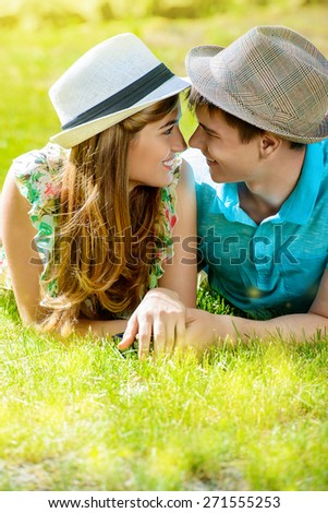 Happy young couple relaxing on the lawn in a summer park. Love concept. Vacation.