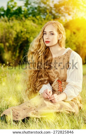 Beautiful girl with magnificent blonde hair wearing simple linen dress. Countryside. Summertime.