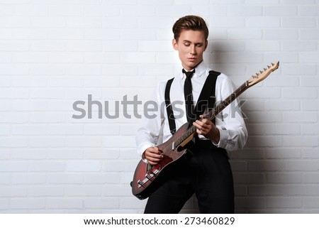 Expressive young man playing rock-n-roll music on his electric guitar. Retro, vintage style.