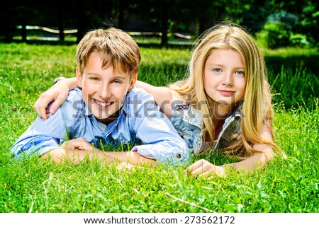 Two cheerful teenagers on the grass in the park. Summer. Friendship.