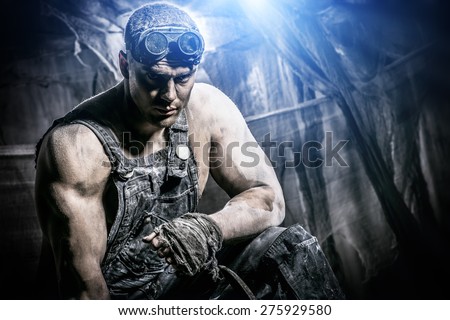 Portrait of a strong muscular man coal miner standing over dark grunge background. Mining industry. Art concept.