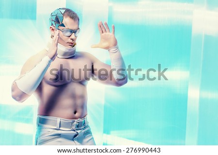 Technologies of the future, man of the future. Handsome muscular man with futuristic make-up wearing glasses stands on a luminous transparent background and touches something virtual.