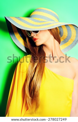 Portrait of a stunning fashionable lady in bright yellow dress posing over  green background. Beauty, fashion concept. Colors of summer.