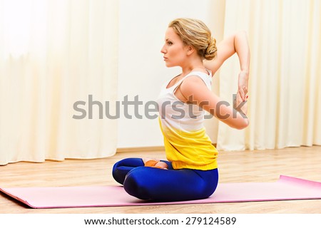 Slender athletic girl doing yoga exercises indoor. Stretching.