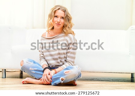 Smiling young woman resting at home on a sofa. Interior.