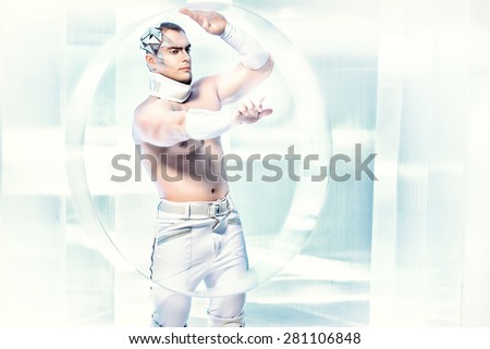 Technologies of the future, man of the future. Handsome muscular man with futuristic make-up stands on a luminous transparent background and touches something virtual.