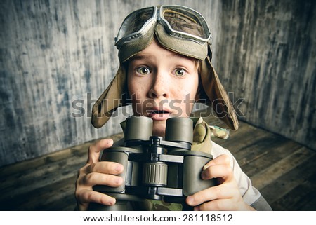 Boy plays the pilot, holding binoculars and surprised. Childhood. Fantasy, imagination.