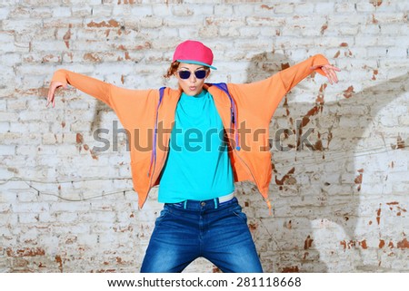 Young stylish girl in the city. Brick wall background. Youth fashion. Hip-hop style.
