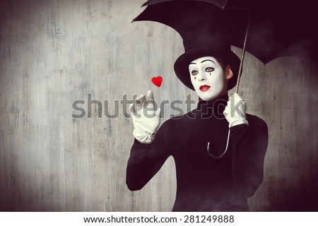 Portrait of a male mime artist standing under umbrella expressing sadness and loneliness. Love. Grunge background.