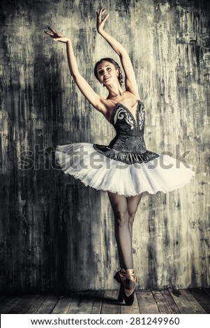 Professional ballet dancer posing at studio over grunge background. Art concept.