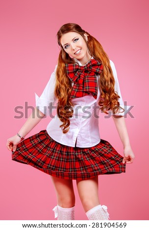 Cute smiling teen girl in school plaid skirt and white blouse posing over pink background. Anime style.
