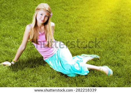 Beautiful teenage girl lying on a green lawn in the park. Harmony. Holiday.
