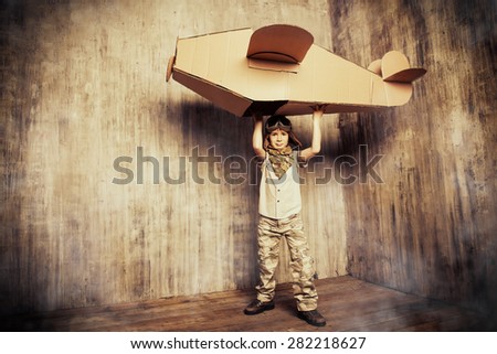 Cute dreamer boy playing with a cardboard airplane. Childhood. Fantasy, imagination. Retro style.