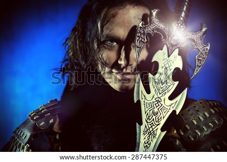 Close-up portrait of the ancient male warrior in armor holding sword. Historical character. Fantasy.