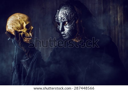 Mysterious man in iron mask holding skull. Steampunk. Fantasy. Halloween.