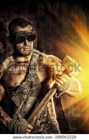 Handsome muscular coal miner with a hammer over dark grunge background. Mining industry. Art concept.