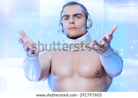 Technologies of the future, man of the future. Handsome muscular man with futuristic make-up in the headphones standing on a luminous transparent background.